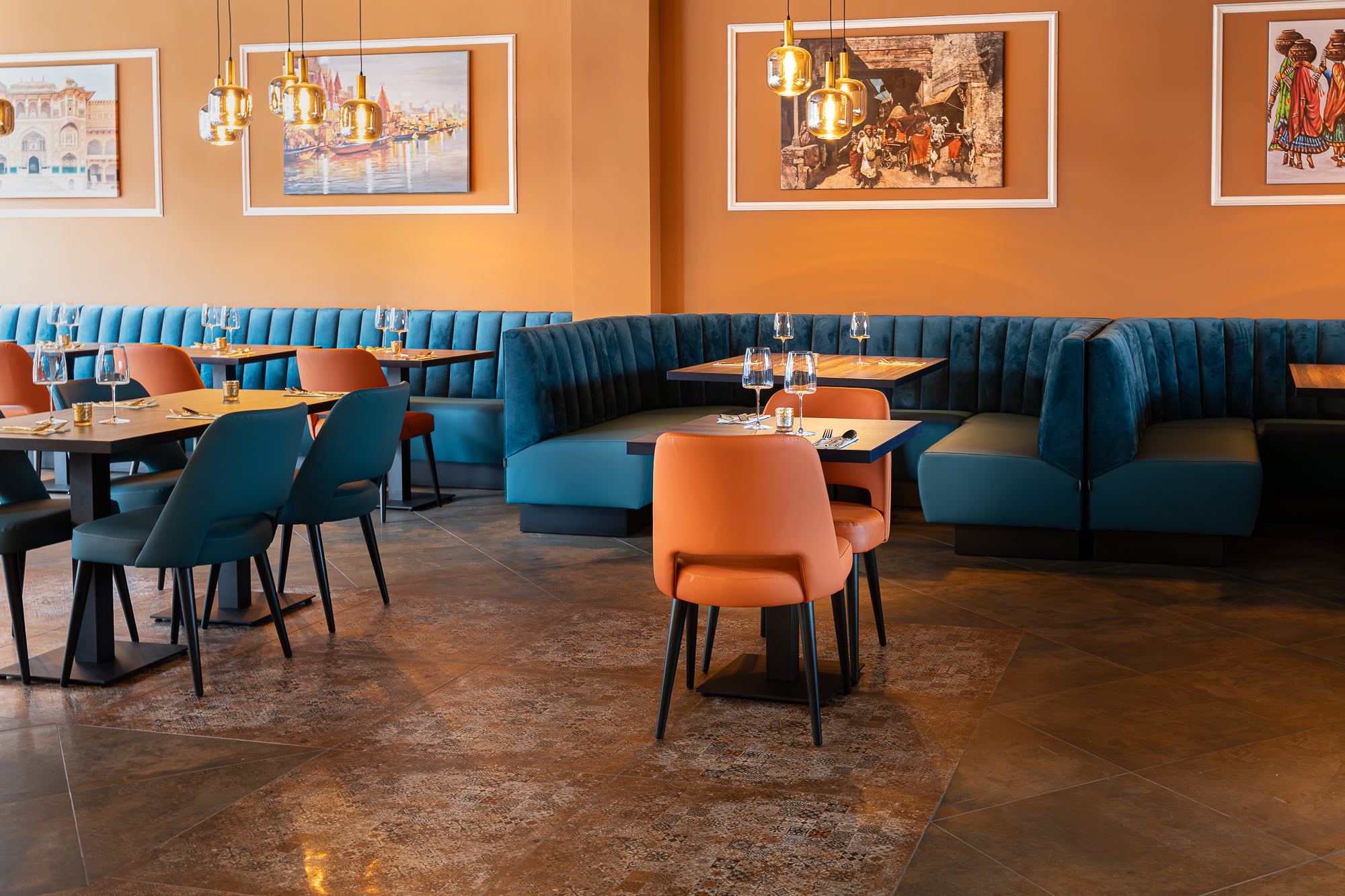 Blauw velvet horecabank in hoekopstelling met oranje stoelen – maatwerk restaurantinrichting Indian Fusion Almere