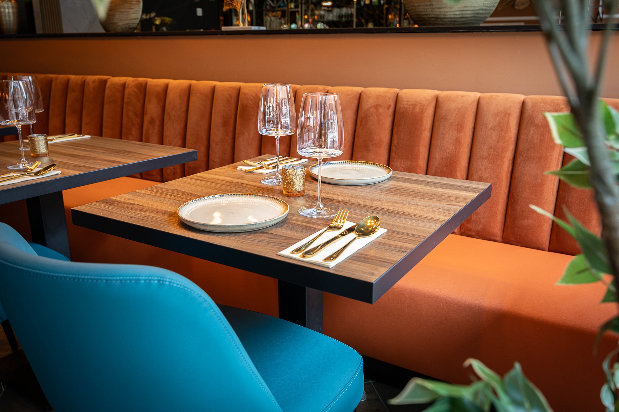 Oranje velvet horecabank met houtlook tafel en turquoise stoel – project Indian Fusion Almere